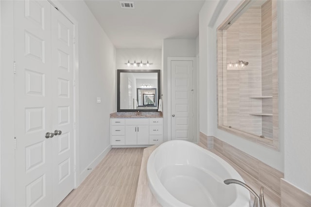 bathroom with tiled tub and vanity