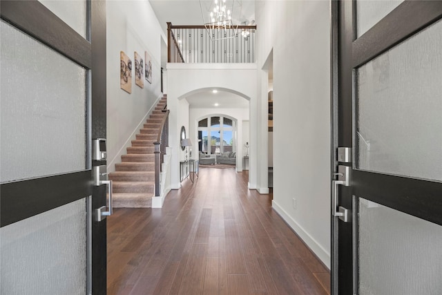 foyer with dark hardwood / wood-style floors, a high ceiling, and an inviting chandelier