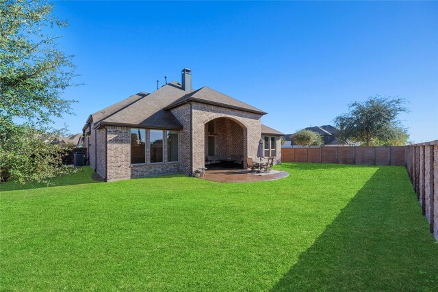 rear view of house featuring a patio, central AC, and a lawn