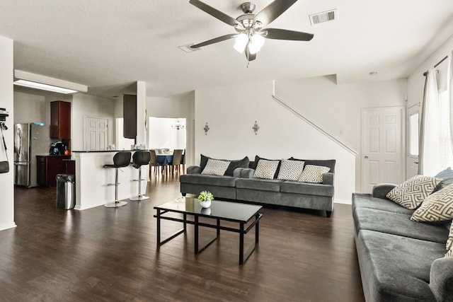 living room featuring ceiling fan and dark hardwood / wood-style flooring