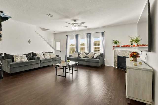 living room with a textured ceiling, ceiling fan, and dark wood-type flooring