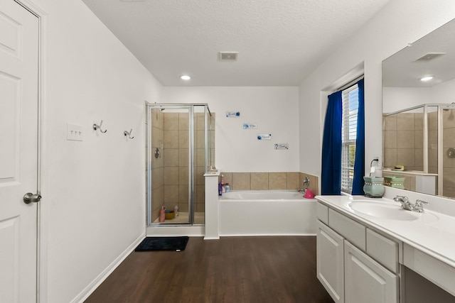 bathroom with vanity, a textured ceiling, hardwood / wood-style flooring, and separate shower and tub