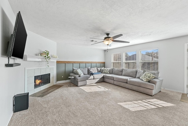 living room with ceiling fan, carpet floors, and a tiled fireplace