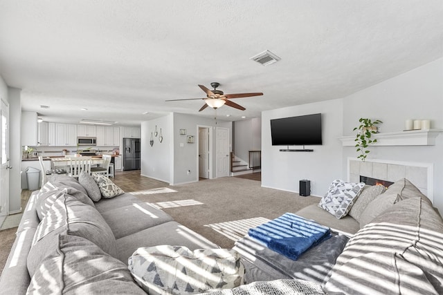 living room with carpet flooring, ceiling fan, and a fireplace