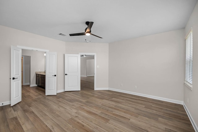 unfurnished bedroom featuring light wood-type flooring, ceiling fan, and connected bathroom