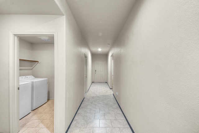 hall with washing machine and clothes dryer and light tile patterned floors