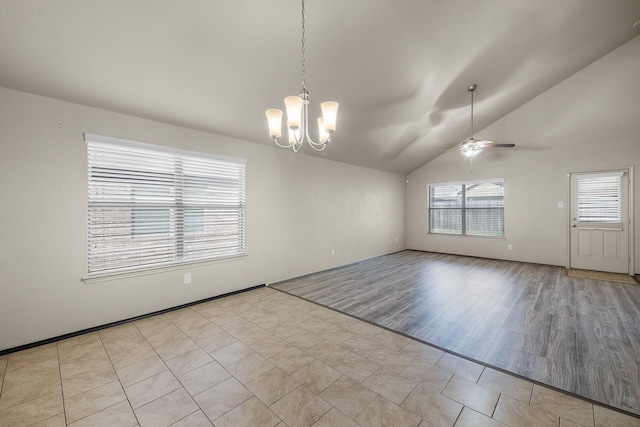 unfurnished room featuring ceiling fan with notable chandelier, light tile patterned flooring, and vaulted ceiling