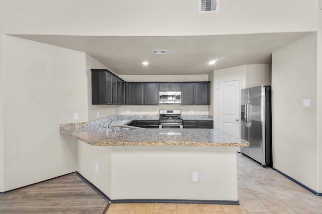 kitchen featuring sink, light stone counters, kitchen peninsula, and stainless steel appliances