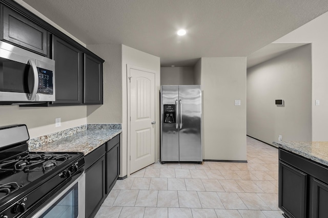 kitchen with light stone countertops, appliances with stainless steel finishes, a textured ceiling, and light tile patterned floors