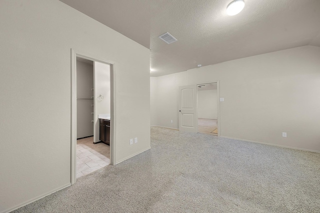 carpeted spare room featuring a textured ceiling and lofted ceiling