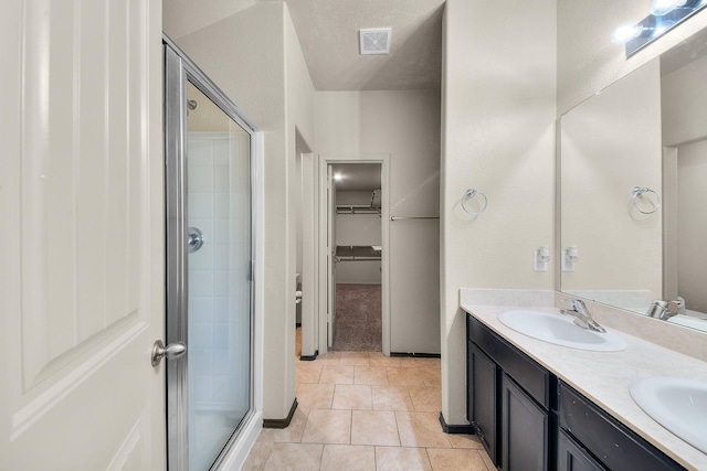 bathroom with tile patterned flooring, a textured ceiling, vanity, and a shower with door