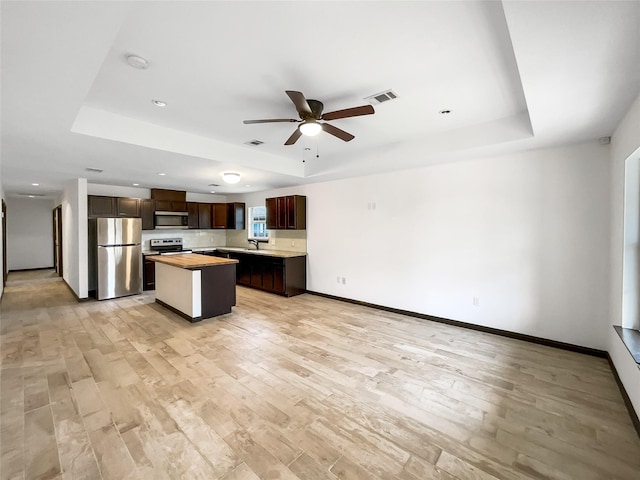 kitchen featuring a tray ceiling, a center island, butcher block countertops, and appliances with stainless steel finishes