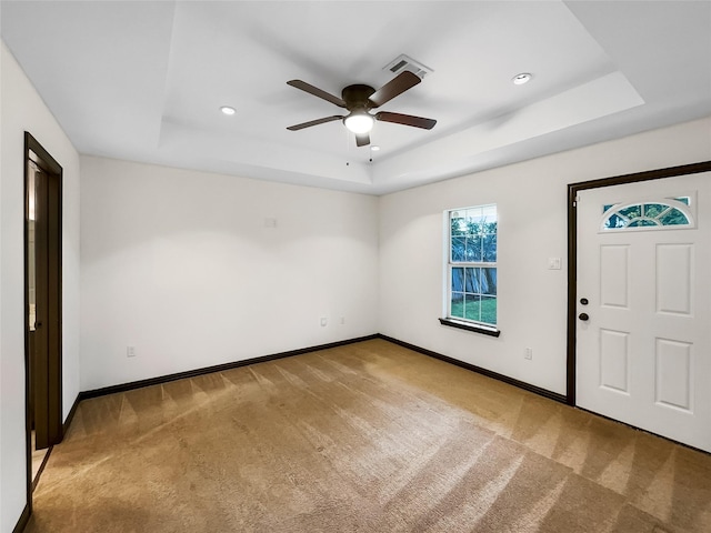 entrance foyer featuring carpet, ceiling fan, and a tray ceiling