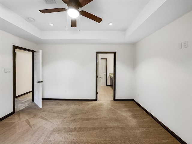 carpeted empty room featuring a raised ceiling and ceiling fan