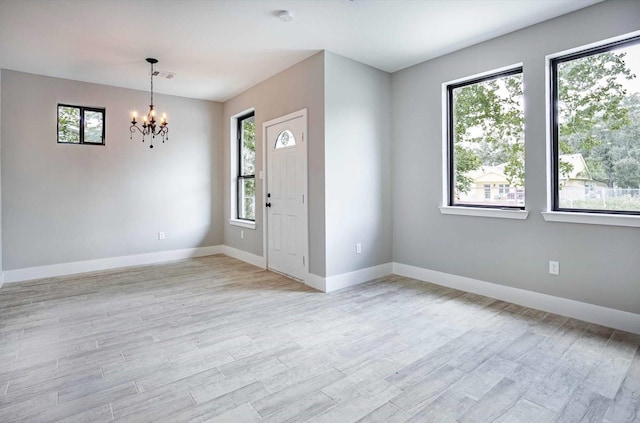 entryway featuring a healthy amount of sunlight, light wood-type flooring, and a notable chandelier