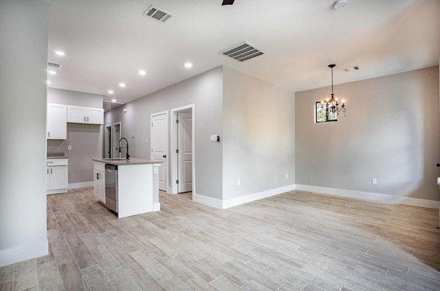 kitchen with a center island with sink, sink, stainless steel dishwasher, white cabinetry, and a chandelier