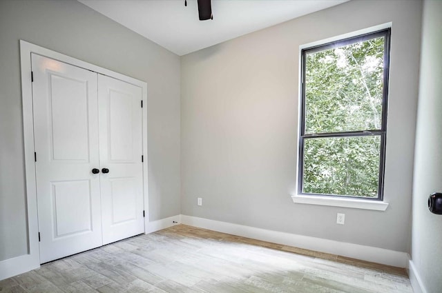 unfurnished bedroom featuring ceiling fan, a closet, and light hardwood / wood-style flooring