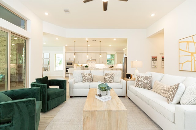 living room featuring a wealth of natural light, light hardwood / wood-style flooring, and ceiling fan