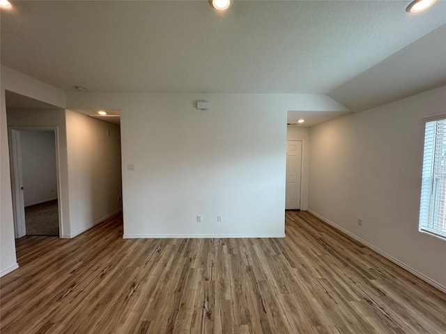 spare room featuring hardwood / wood-style floors and lofted ceiling