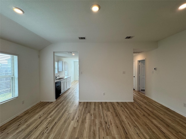 unfurnished room with light wood-type flooring, sink, and vaulted ceiling