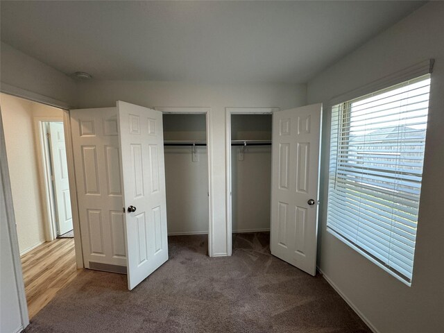 unfurnished bedroom featuring carpet flooring and multiple closets