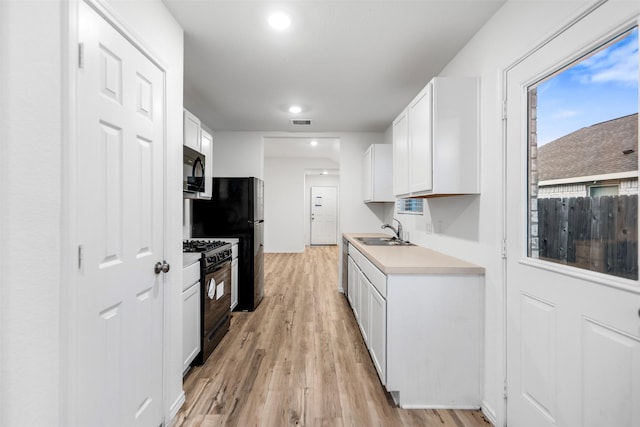 14534 Broadbury Pond Rd, Rosharon, TX 77583 - kitchen featuring black appliances, a sink, light wood-type flooring, white cabinetry, and light countertops