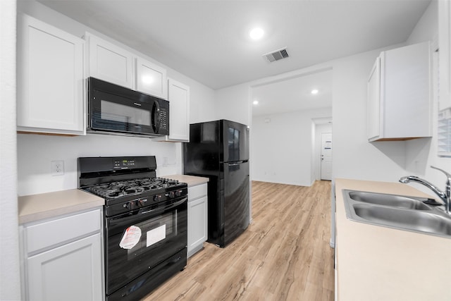 14534 Broadbury Pond Rd, Rosharon, TX 77583 - kitchen with black appliances, a sink, white cabinets, light wood-type flooring, and light countertops