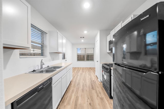 14534 Broadbury Pond Rd, Rosharon, TX 77583 - kitchen featuring black appliances, a sink, light wood-style floors, white cabinets, and healthy amount of natural light