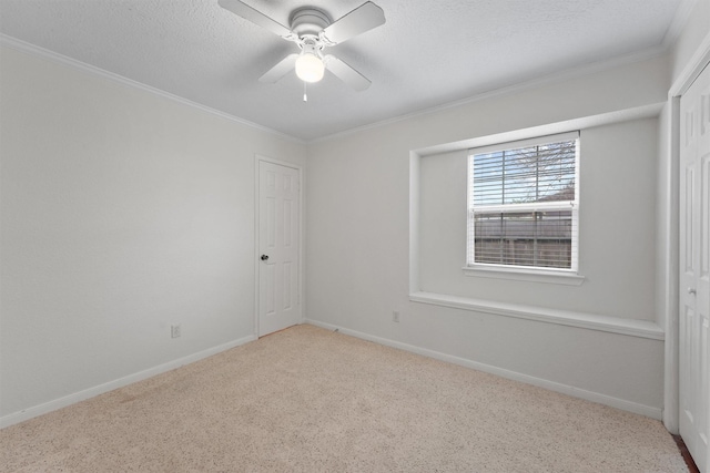 carpeted empty room featuring ceiling fan, a textured ceiling, and ornamental molding