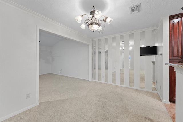 carpeted spare room featuring a textured ceiling, crown molding, and a notable chandelier