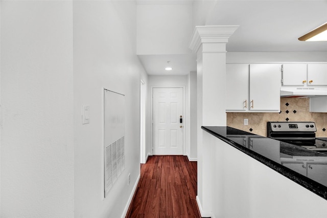 kitchen with tasteful backsplash, stainless steel range with electric stovetop, dark stone countertops, dark hardwood / wood-style floors, and white cabinetry