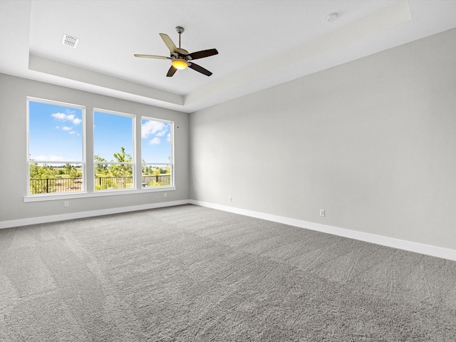 carpeted spare room with ceiling fan and a tray ceiling