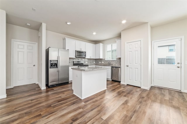 kitchen featuring a kitchen island, light stone counters, white cabinetry, and appliances with stainless steel finishes