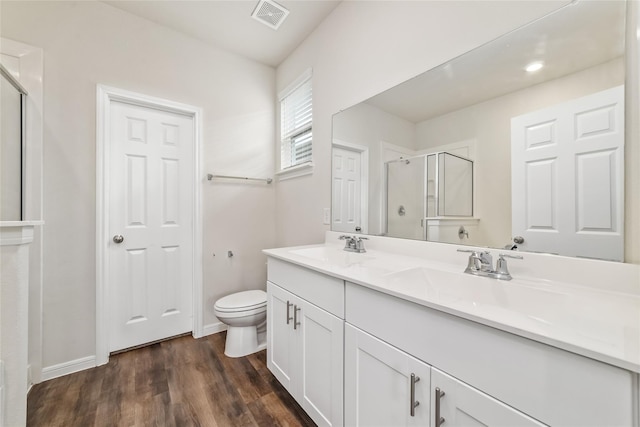 bathroom featuring a shower with door, vanity, wood-type flooring, and toilet