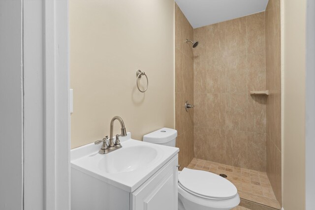 bathroom featuring a tile shower, vanity, and toilet