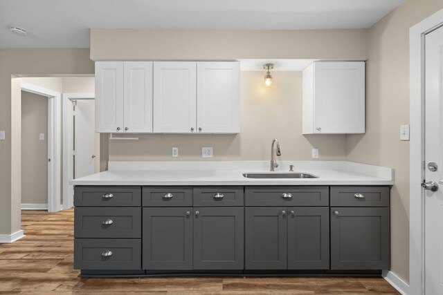 kitchen with sink, dark wood-type flooring, gray cabinets, and white cabinets