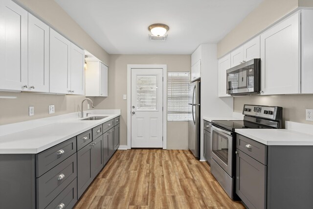 kitchen with gray cabinetry, sink, white cabinetry, and stainless steel appliances