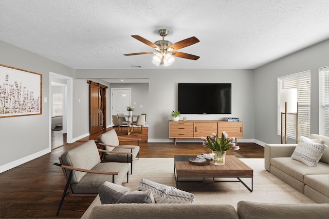 living room with a barn door, hardwood / wood-style floors, a textured ceiling, and ceiling fan