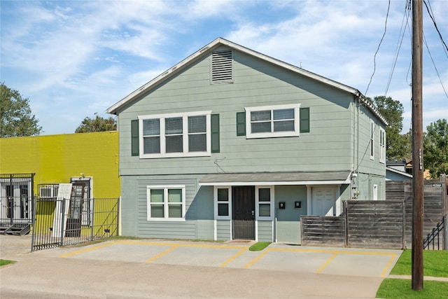 view of front of house with uncovered parking, fence, and a gate