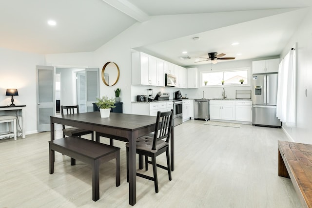 dining room featuring vaulted ceiling with beams, light hardwood / wood-style flooring, ceiling fan, and sink