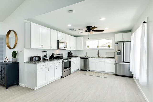 kitchen with sink, stainless steel appliances, light stone counters, light hardwood / wood-style flooring, and white cabinets