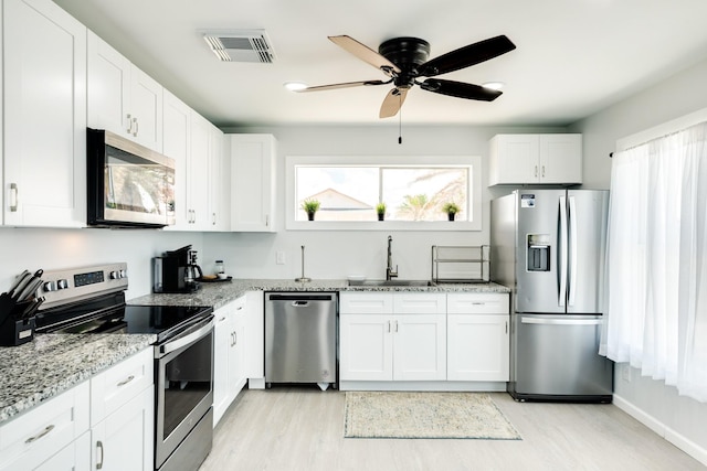 kitchen with light stone countertops, white cabinetry, sink, and stainless steel appliances