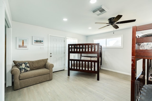 bedroom with ceiling fan, a nursery area, and light wood-type flooring