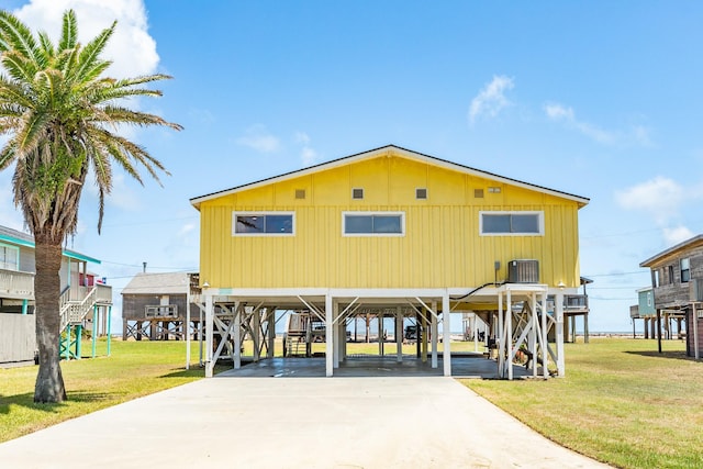 view of front of property with cooling unit, a front yard, and a carport