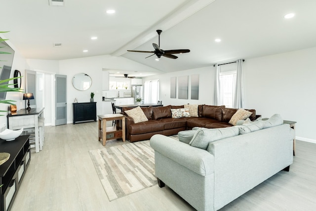 living room with a wealth of natural light, ceiling fan, lofted ceiling with beams, and light wood-type flooring