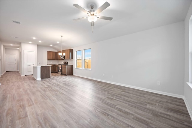 unfurnished living room featuring hardwood / wood-style floors, ceiling fan with notable chandelier, and vaulted ceiling