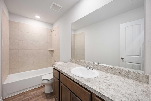 full bathroom with vanity, tiled shower / bath combo, hardwood / wood-style flooring, and toilet