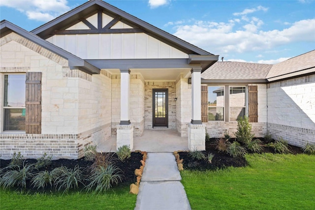 view of exterior entry featuring a lawn and a porch