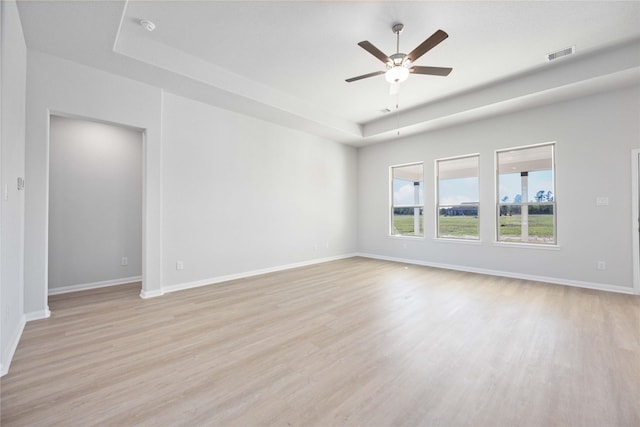 spare room featuring light hardwood / wood-style floors, a raised ceiling, and ceiling fan