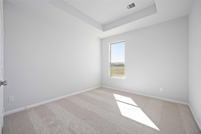 carpeted spare room with a tray ceiling